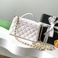White quilted handbag with gold chain and Chanel gift box on a white surface