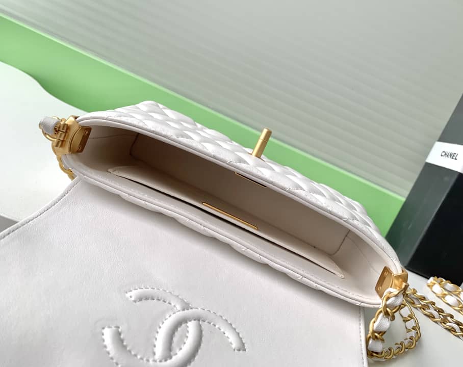 Close-up of a Chanel handbag with gold chain detail on a green surface.