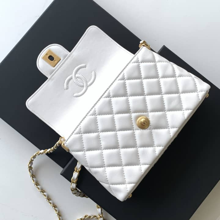 White quilted handbag with gold chain and clasp on a black box