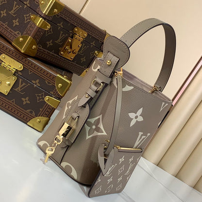 Louis Vuitton handbag with monogram pattern next to a matching suitcase on a light background