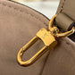 Gold Louis Vuitton bag charm on a beige handbag