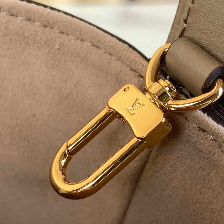 Gold Louis Vuitton bag charm on a beige handbag