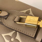 Close-up of a gray leather bag with a gold lock featuring a brand logo.