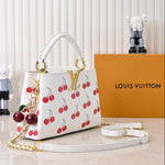 Louis Vuitton handbag with cherry pattern on a white surface with a Louis Vuitton box in the background.
