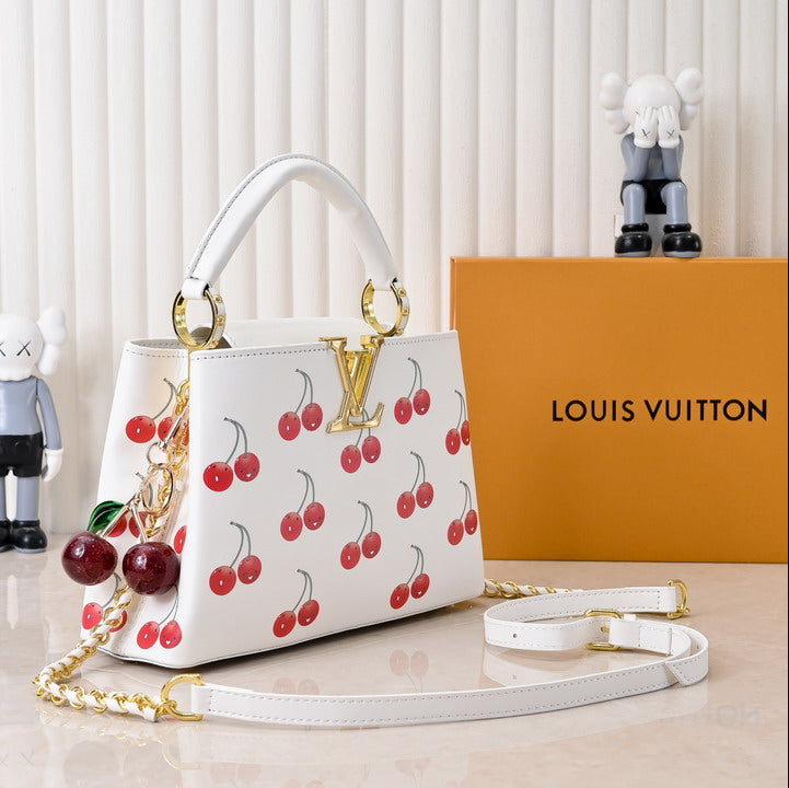 Louis Vuitton handbag with cherry pattern on a white surface with a Louis Vuitton box in the background.