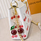 Louis Vuitton handbag with cherry design and keychain on a light background