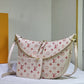 Designer handbag with monogram pattern on a white surface with a Louis Vuitton box in the background.