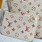 White handbag with red and beige monogram pattern on a light gray surface.