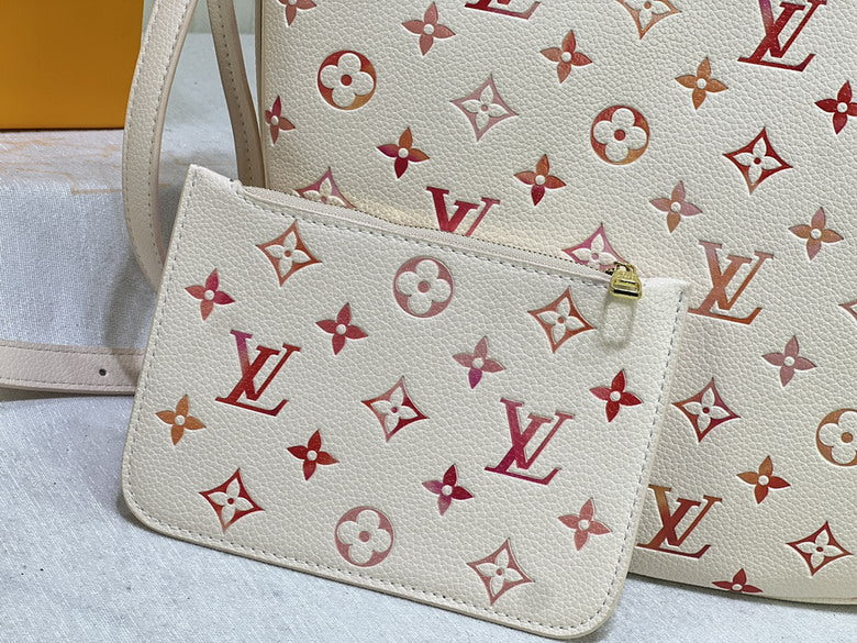 White handbag with red and beige monogram pattern on a light gray surface.