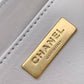 Gold Chanel label on a gray leather surface