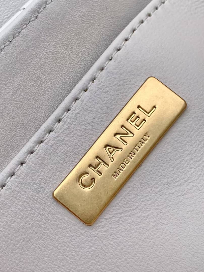 Gold Chanel label on a gray leather surface