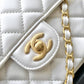 White quilted handbag with gold chain and logo on a black background